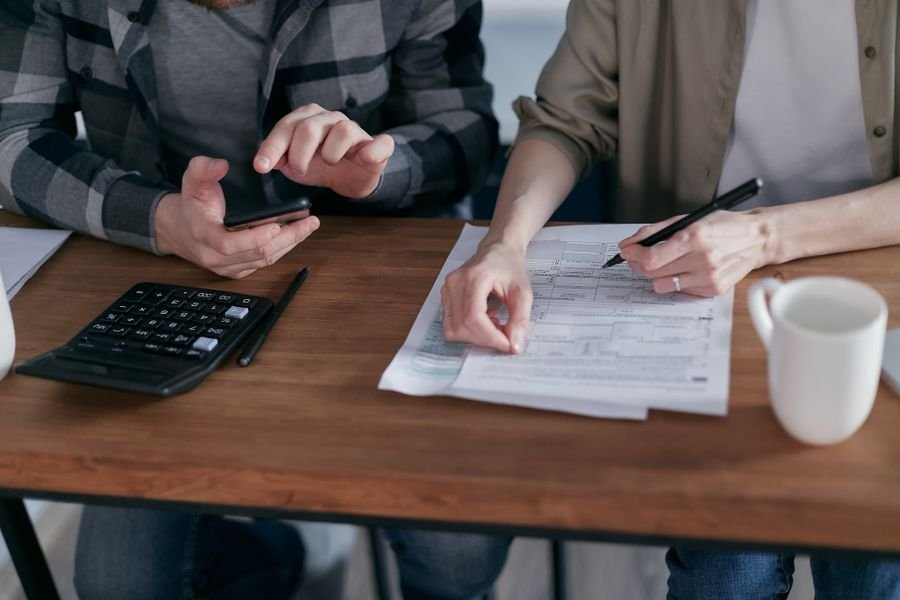 Two people reviewing accounts with a calculator and documents